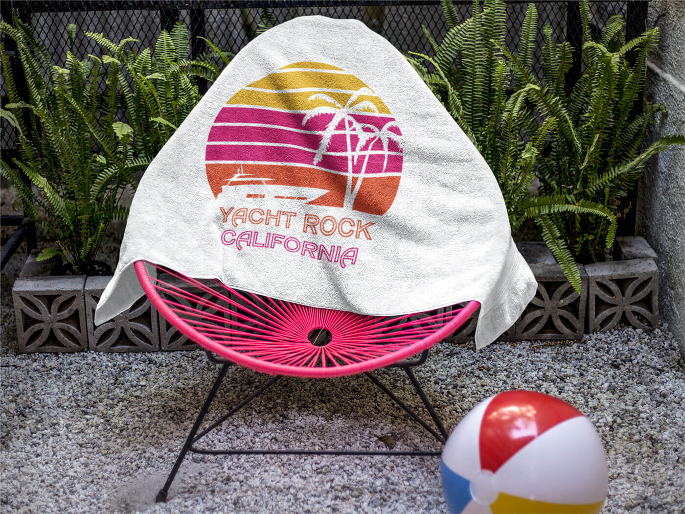 A Yacht Rock California style beach towel sitting on an outside papasan chair.